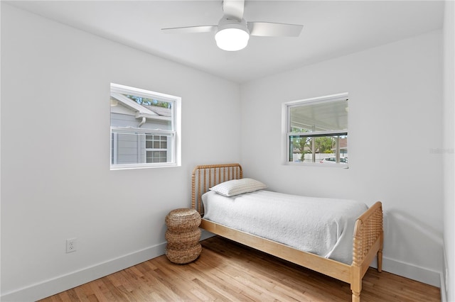 bedroom with a ceiling fan, wood finished floors, and baseboards