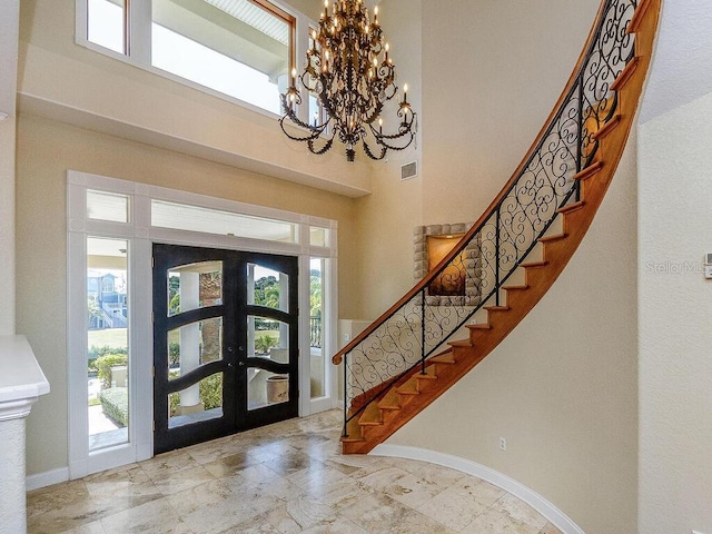 foyer featuring a healthy amount of sunlight, french doors, baseboards, and a towering ceiling