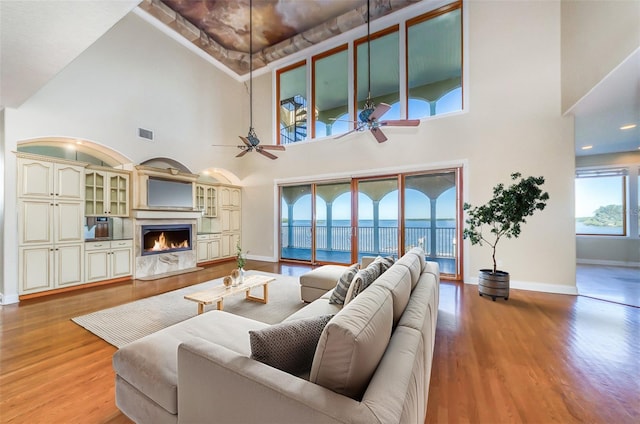 living area featuring a premium fireplace, baseboards, visible vents, and light wood finished floors