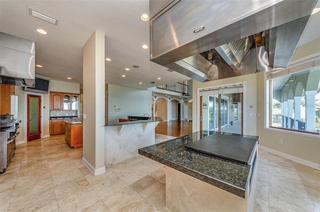 kitchen with brown cabinetry, visible vents, range with two ovens, dark countertops, and tasteful backsplash