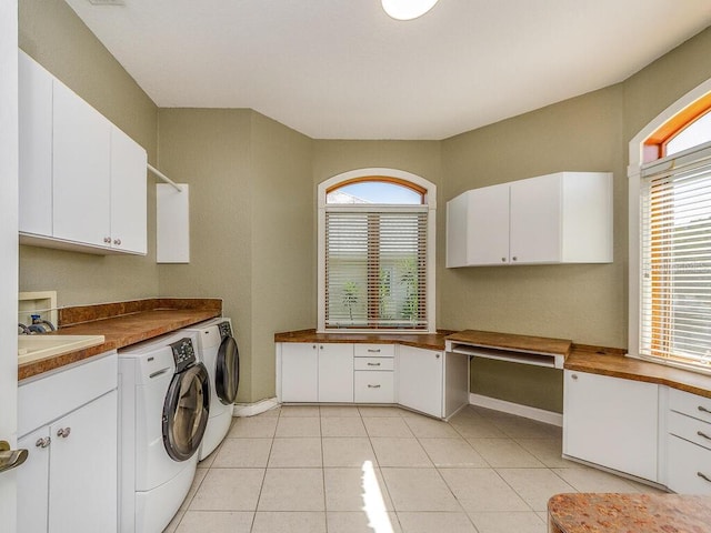 clothes washing area with light tile patterned floors, baseboards, washing machine and clothes dryer, cabinet space, and a sink