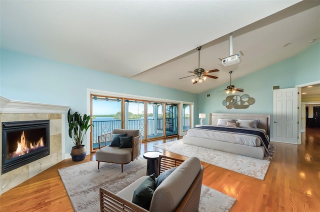 bedroom featuring access to exterior, a fireplace, high vaulted ceiling, and wood finished floors