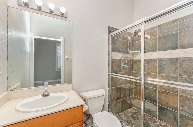 full bathroom with a stall shower, toilet, vanity, and a textured wall