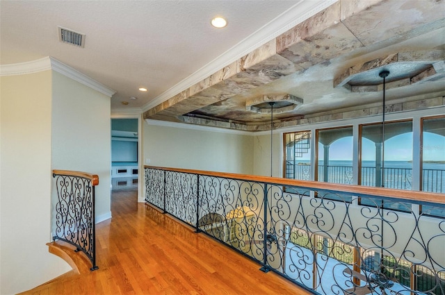 hall with wood finished floors, visible vents, recessed lighting, a water view, and crown molding