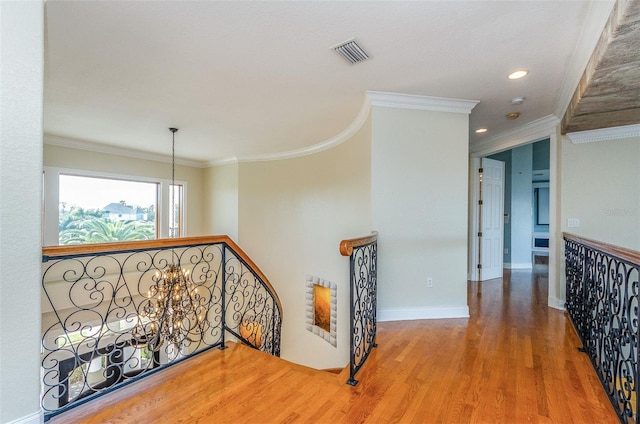 hallway featuring visible vents, an upstairs landing, ornamental molding, wood finished floors, and baseboards