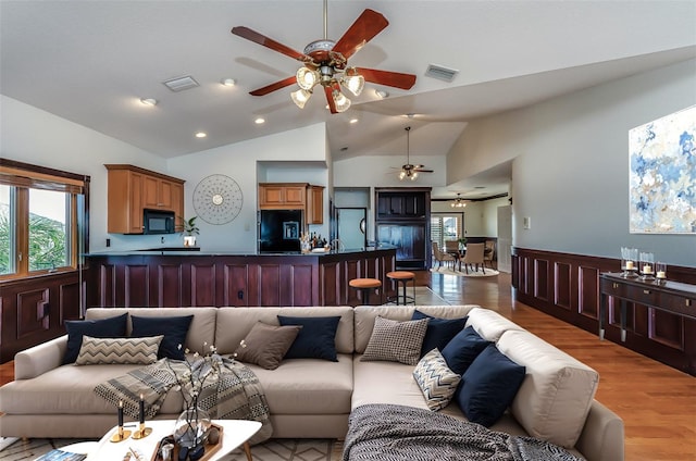 living room featuring light wood finished floors, visible vents, and vaulted ceiling