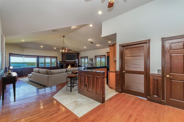 kitchen featuring dark countertops, a ceiling fan, light wood-style floors, and vaulted ceiling