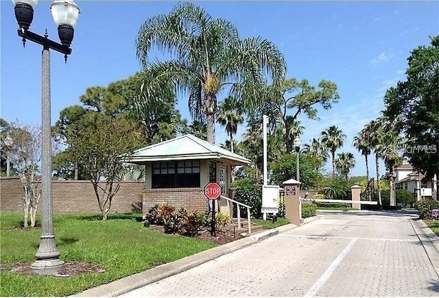 exterior space with a gated entry, curbs, and street lights