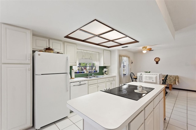 kitchen with white appliances, a kitchen island, white cabinets, and light countertops