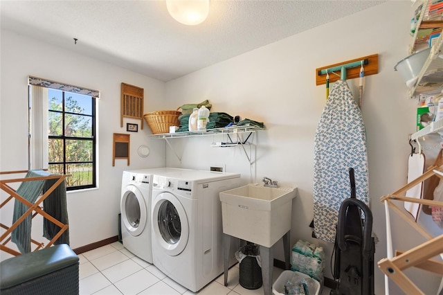 laundry area featuring baseboards, light tile patterned floors, laundry area, a textured ceiling, and separate washer and dryer