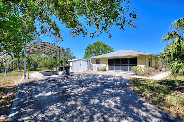 view of front of property with a storage unit, stucco siding, a detached carport, an outdoor structure, and concrete driveway