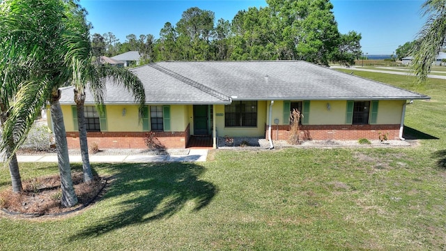 single story home featuring brick siding, stucco siding, a front yard, and roof with shingles