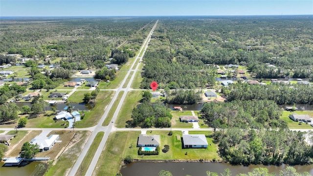 birds eye view of property with a residential view, a wooded view, and a water view