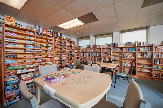 carpeted office featuring wall of books and a paneled ceiling