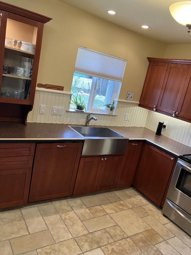 kitchen with a wainscoted wall, recessed lighting, a sink, stone finish floor, and range