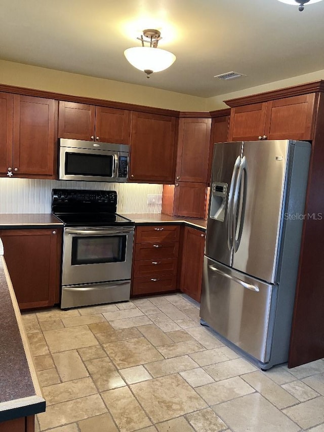 kitchen with visible vents, appliances with stainless steel finishes, and stone finish flooring