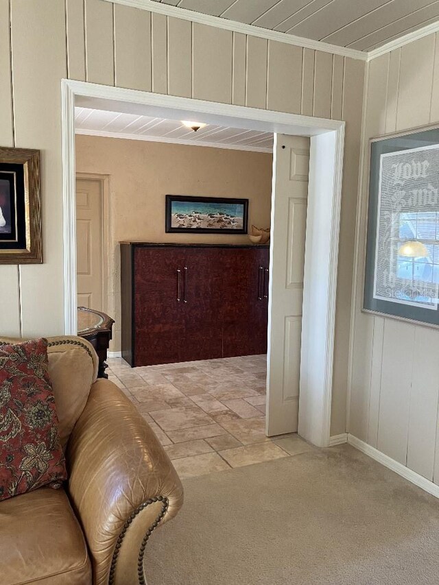 interior space featuring light carpet, a decorative wall, and ornamental molding