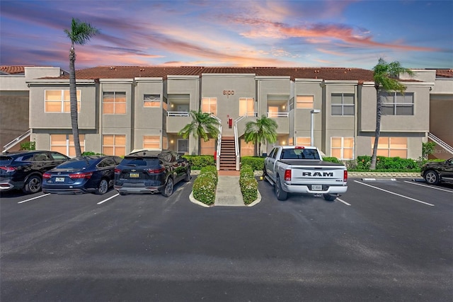 property at dusk featuring stairs and uncovered parking