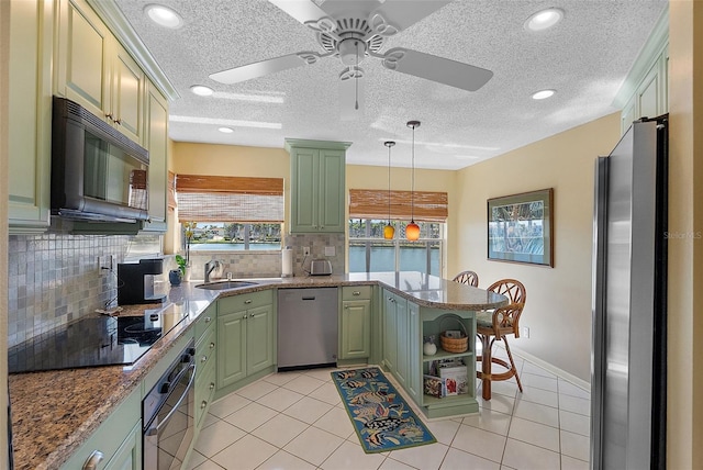 kitchen featuring a sink, a peninsula, black appliances, and green cabinetry