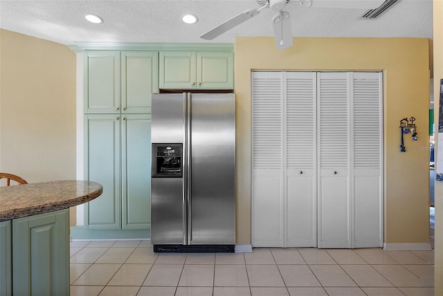 kitchen featuring light tile patterned floors, visible vents, green cabinets, and stainless steel fridge with ice dispenser