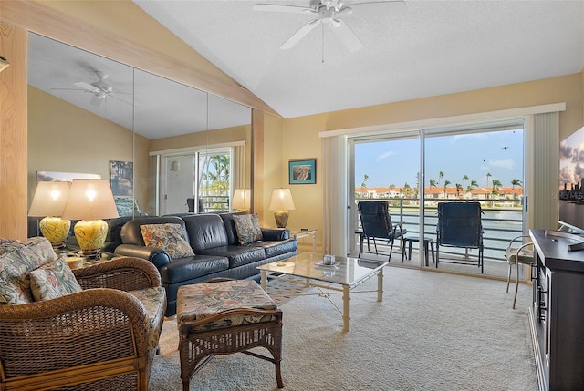 carpeted living area with a textured ceiling, a ceiling fan, and vaulted ceiling