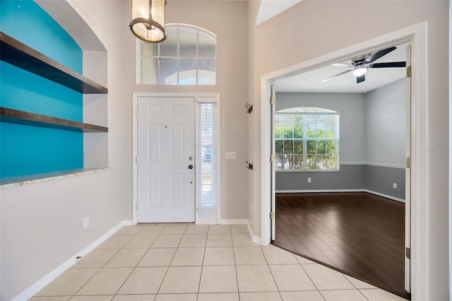 foyer featuring light tile patterned flooring, baseboards, and ceiling fan