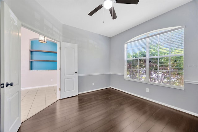 spare room with a ceiling fan, wood finished floors, and baseboards