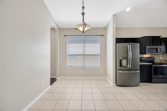 kitchen with tasteful backsplash, appliances with stainless steel finishes, light tile patterned flooring, arched walkways, and dark cabinets