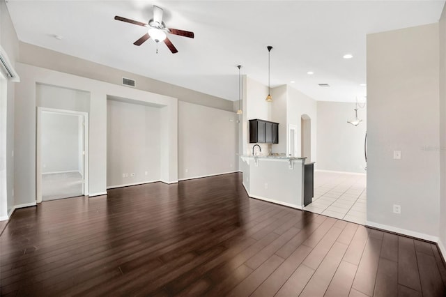 unfurnished living room featuring dark wood-style floors, visible vents, recessed lighting, arched walkways, and ceiling fan