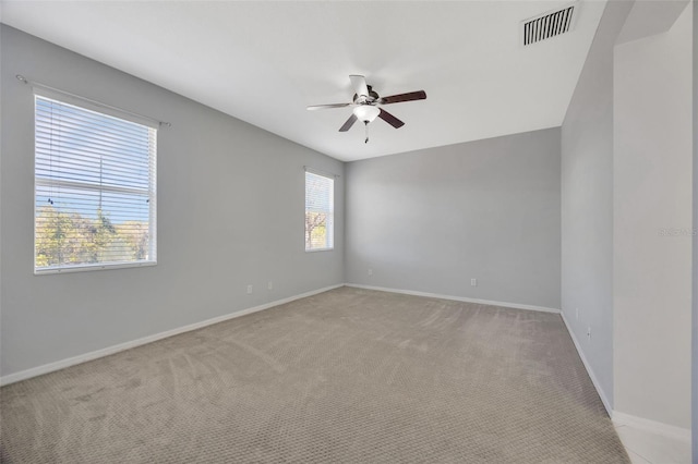 empty room with light carpet, visible vents, baseboards, and ceiling fan