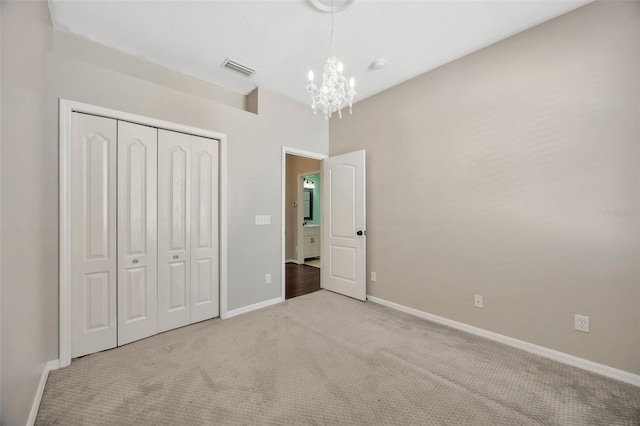 unfurnished bedroom with visible vents, baseboards, carpet floors, a closet, and a notable chandelier