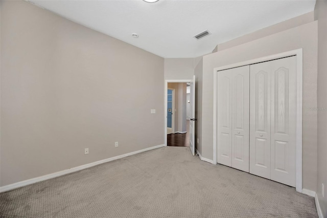 unfurnished bedroom with visible vents, baseboards, light colored carpet, and a closet