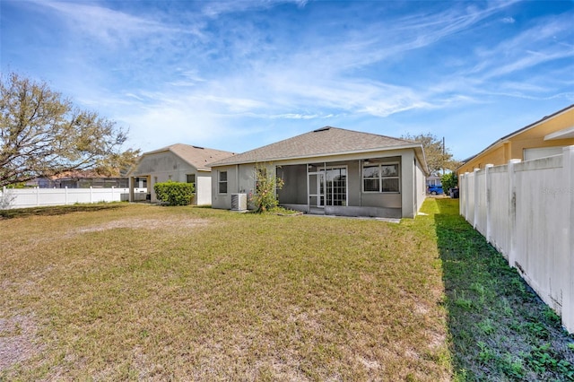 rear view of property featuring fence, central air condition unit, a lawn, stucco siding, and a sunroom