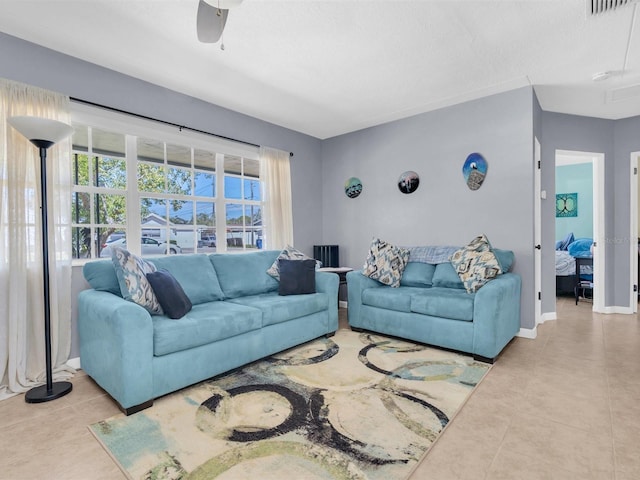 living room with tile patterned floors, visible vents, baseboards, and a ceiling fan