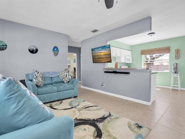 living room with light tile patterned floors, visible vents, a ceiling fan, and baseboards