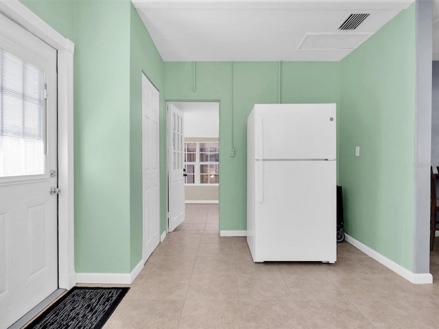 kitchen with light tile patterned floors, baseboards, visible vents, and freestanding refrigerator