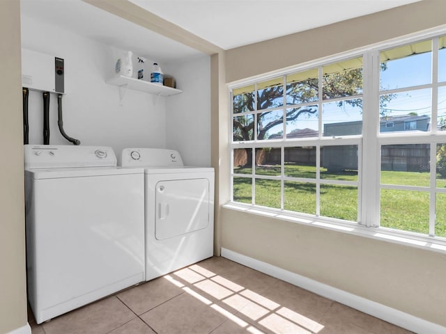 laundry room featuring baseboards, a healthy amount of sunlight, laundry area, and washing machine and clothes dryer