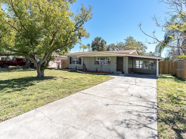 single story home featuring driveway, a carport, a front yard, and fence