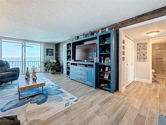 living room with light wood-style flooring, a textured ceiling, and baseboards