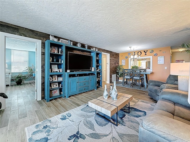 living room featuring a notable chandelier, a healthy amount of sunlight, wood tiled floor, and a textured ceiling