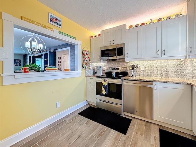 kitchen featuring a chandelier, decorative backsplash, stainless steel appliances, and wood finish floors