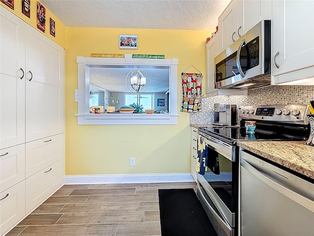 kitchen with wood tiled floor, backsplash, appliances with stainless steel finishes, and a textured ceiling