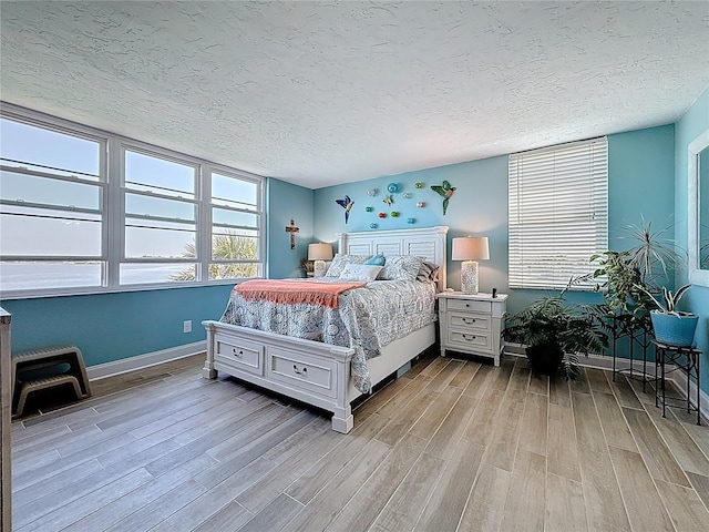 bedroom featuring baseboards, a textured ceiling, and wood finished floors