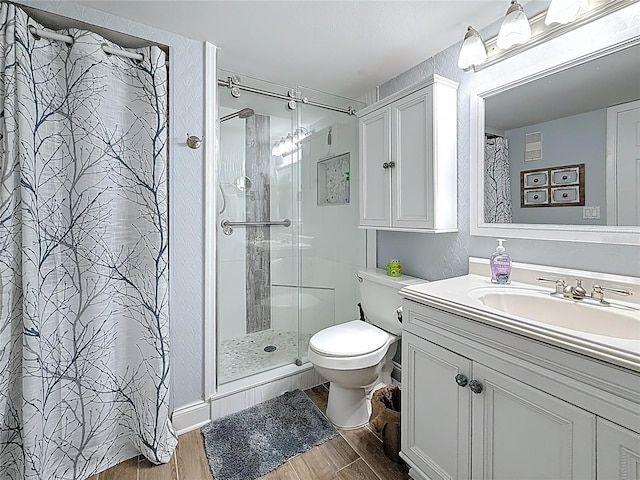 bathroom featuring vanity, a shower stall, toilet, and wood finished floors