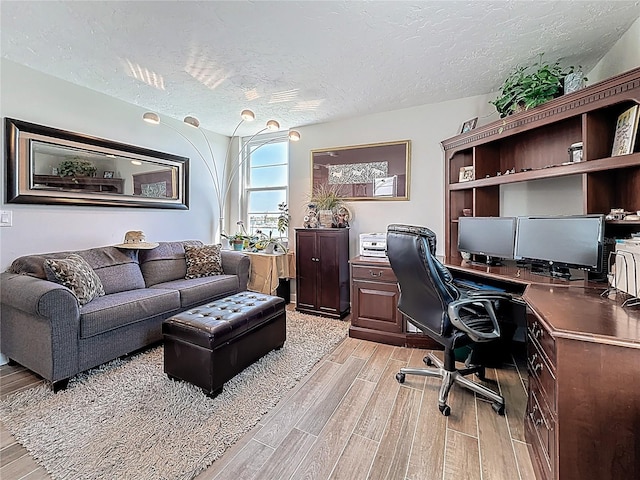 office area featuring light wood-type flooring and a textured ceiling