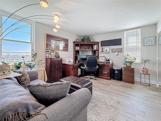 office with a textured ceiling, baseboards, and wood finish floors