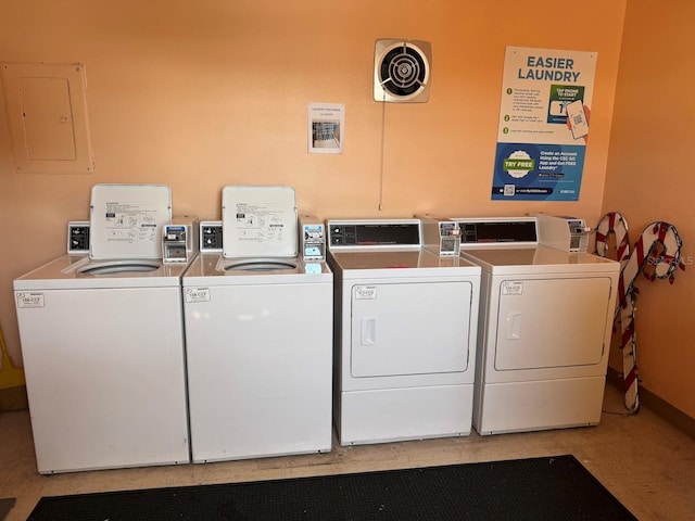 community laundry room featuring electric panel, washing machine and dryer, and baseboards