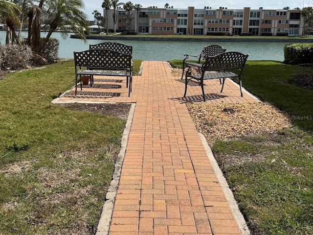 view of property's community with a lawn and a water view