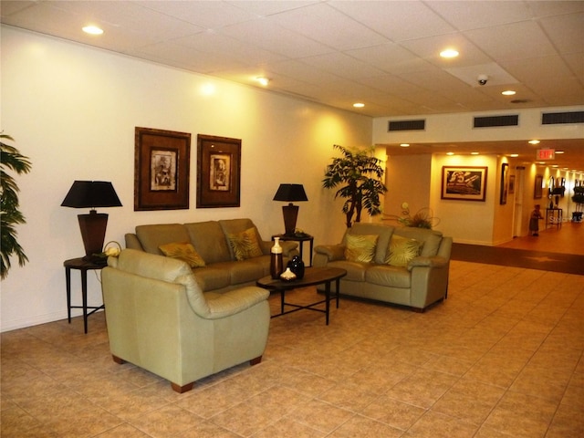 living area with a paneled ceiling, visible vents, and baseboards