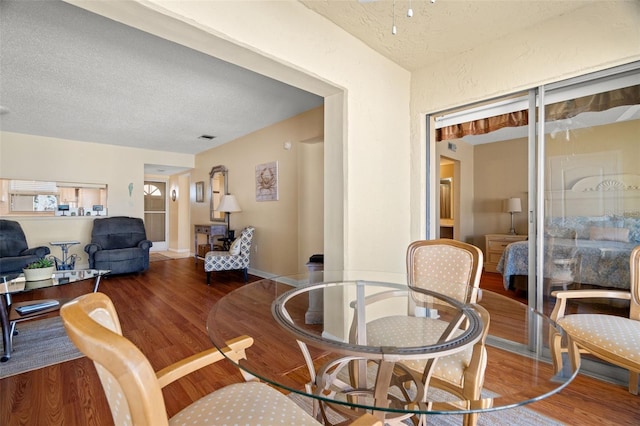 dining area featuring baseboards, wood finished floors, visible vents, and a textured ceiling